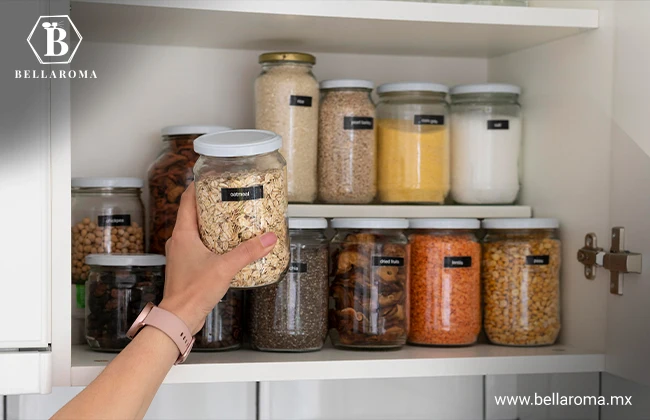 Mano organizando frascos de vidrio con distintos alimentos en una despensa